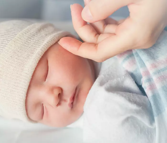 Uma mão acariciando o rosto e causando sono em um bebê dormindo