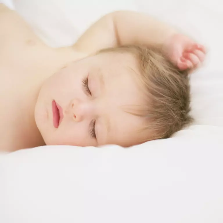 Bebê dormindo em uma cama branca