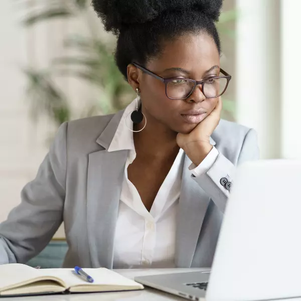 Mulher com trajes sociais atenta à tela de um notebook
